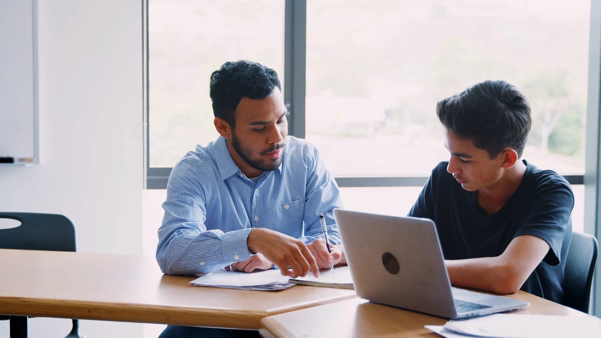 A tutor working one-to-one with a student at a desk