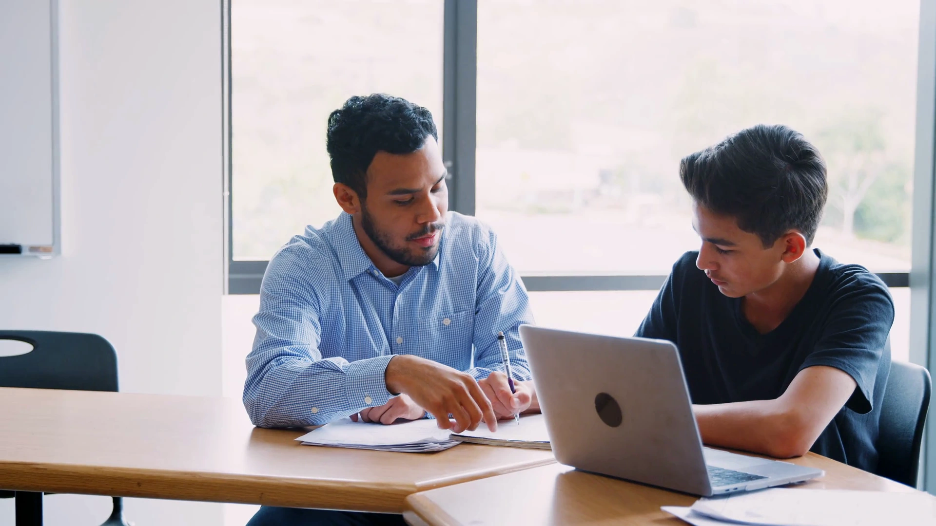 A tutor working through answers one to one with a student at a desk